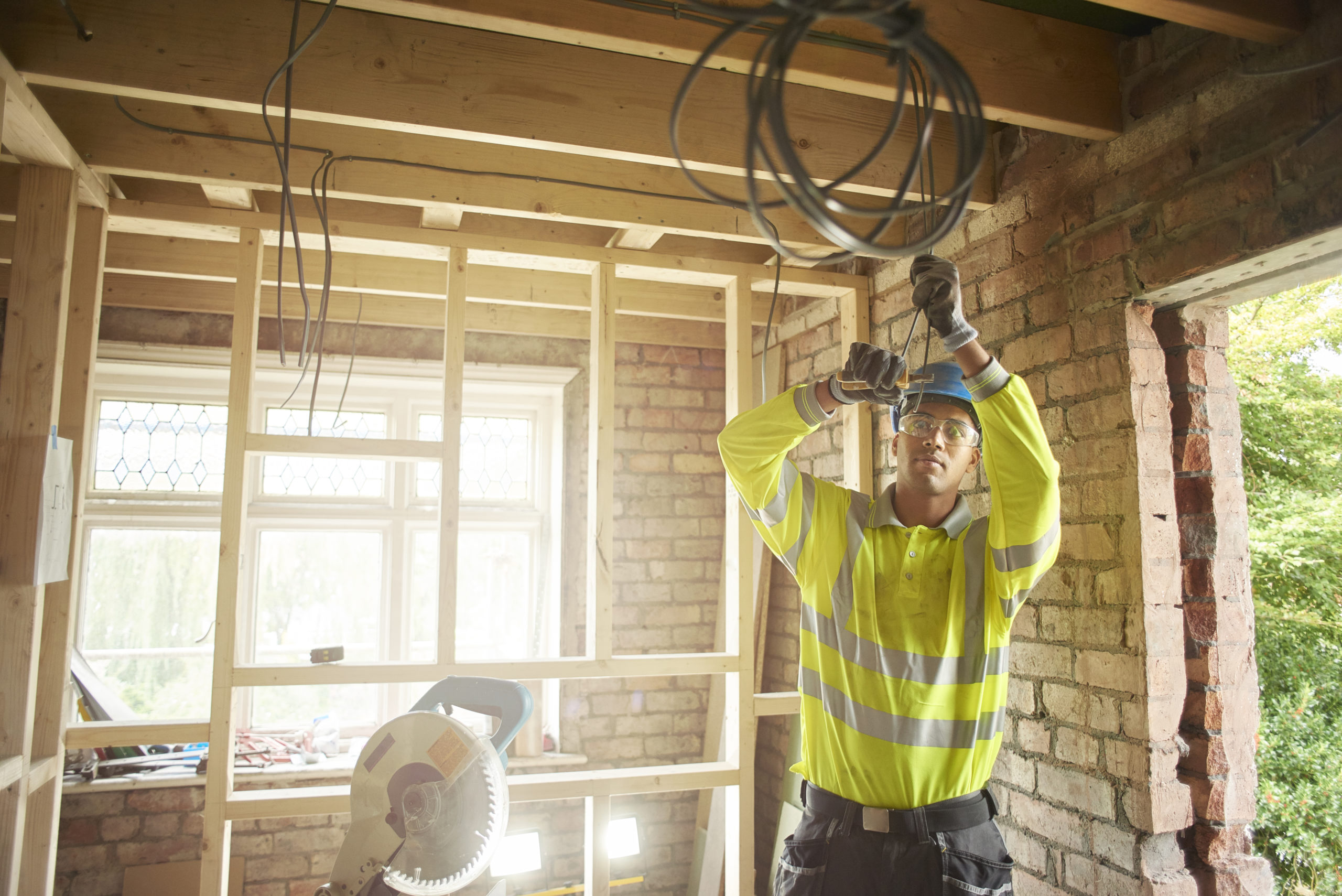 a young male carpenter clipping electrical wires on a first fix