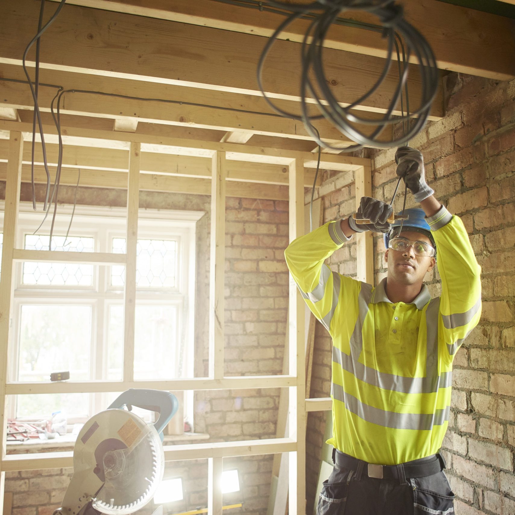 a young male carpenter clipping electrical wires on a first fix